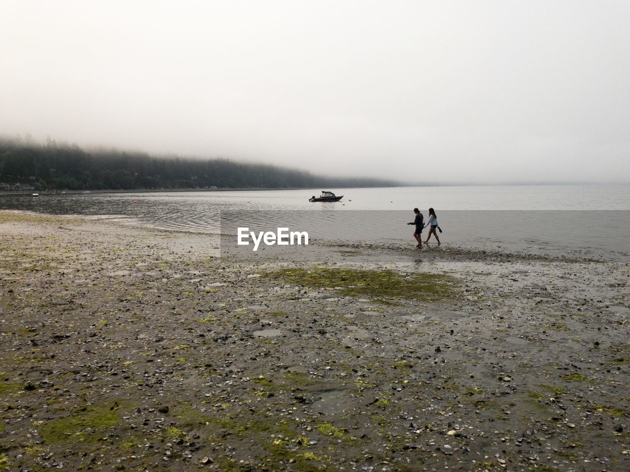 MEN WALKING ON SHORE AGAINST SKY