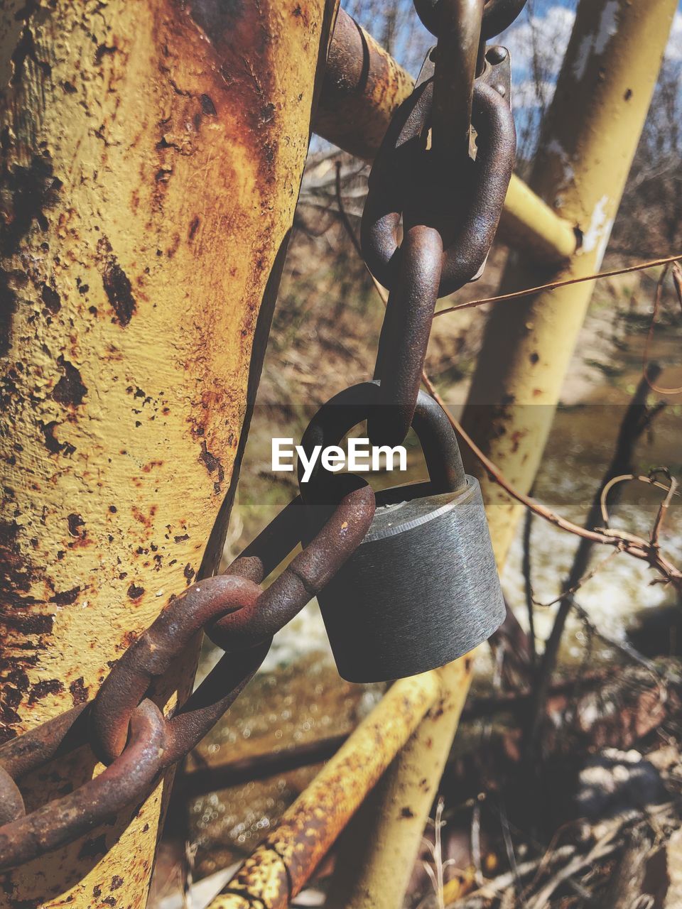 Close-up of rusty chain hanging on metal fence