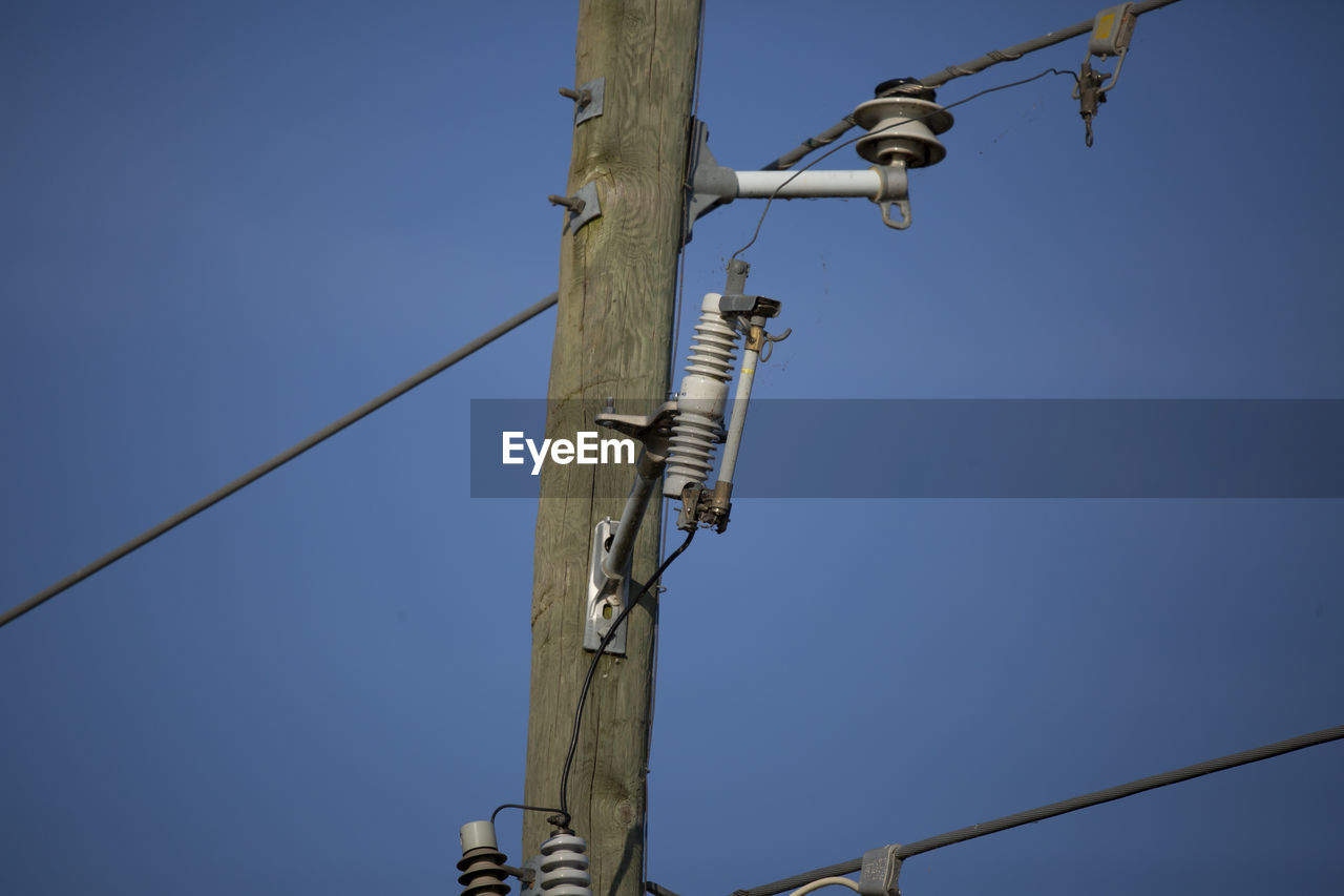 Electrical wires running through the sky, anchored by an electrical pole