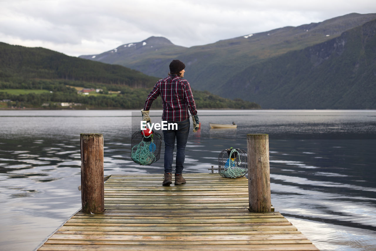 A man holding a crab pot off a dock in norway