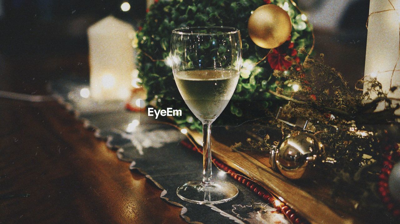 Close-up of wineglass by christmas decorations on table at home