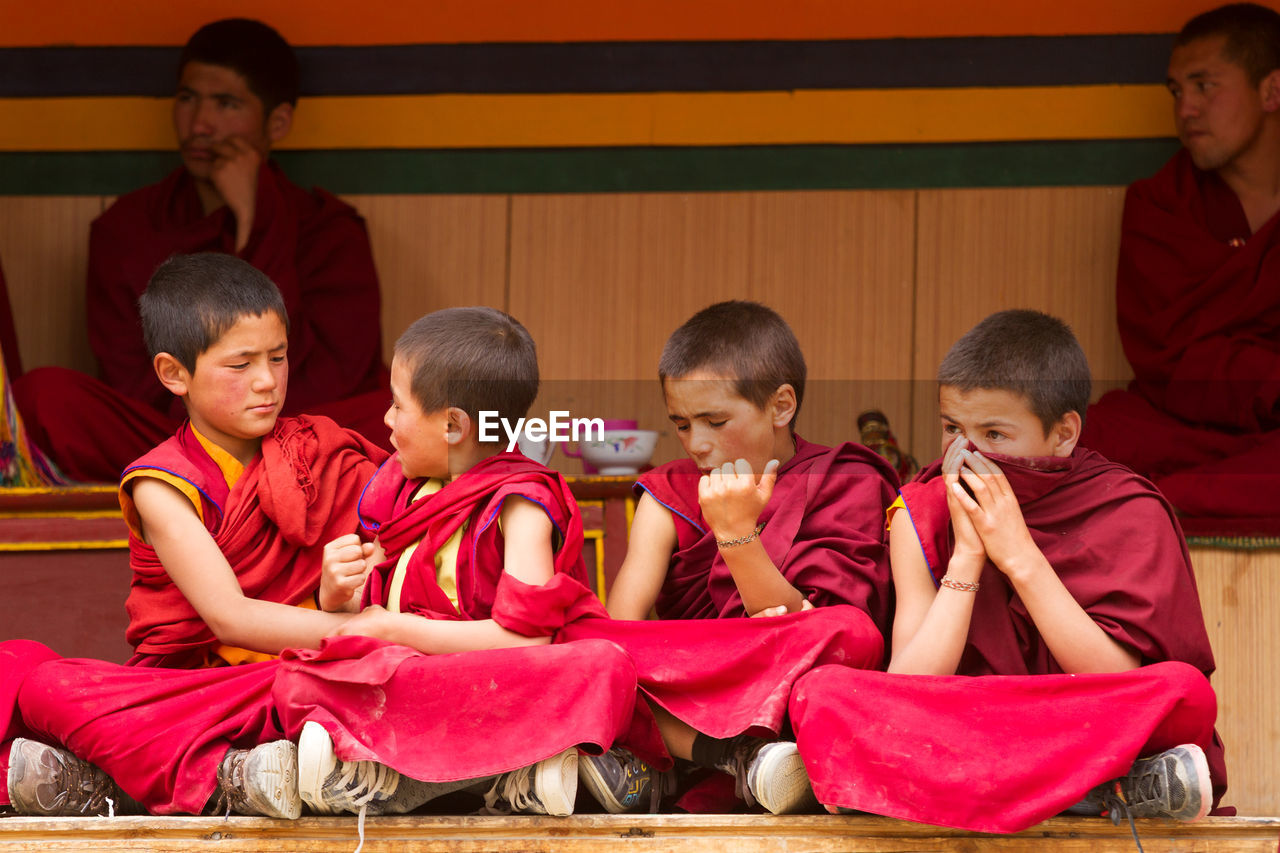 GROUP OF PEOPLE IN TRADITIONAL CLOTHING SITTING