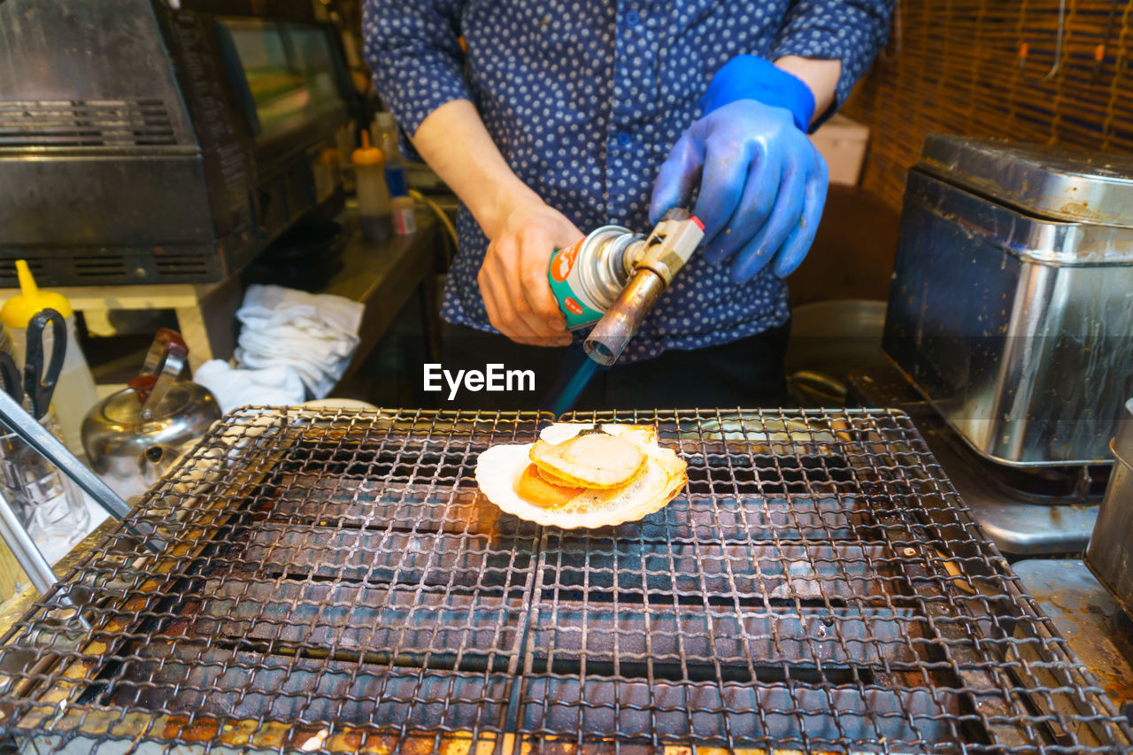 Midsection of man preparing food on barbecue