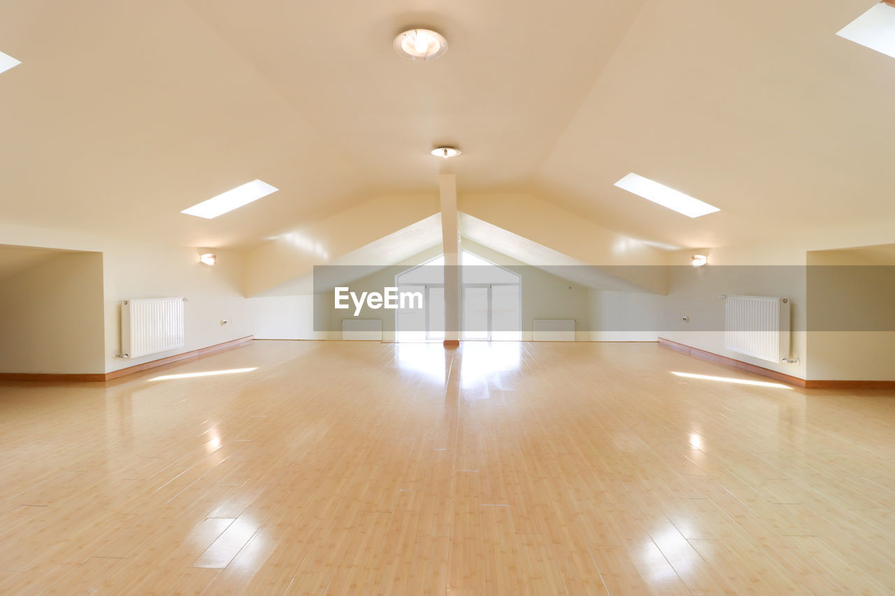 indoors, architecture, flooring, floor, home interior, ceiling, building, lighting equipment, window, built structure, wood flooring, no people, room, daylighting, hardwood floor, wood, hardwood, empty, domestic room, illuminated, home ownership, sparse, laminate flooring, home, real estate, white, parquet floor