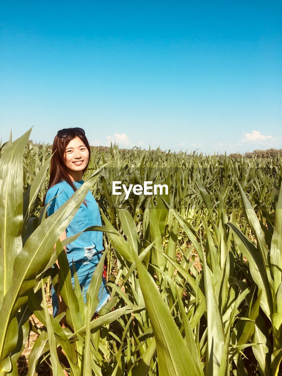 Portrait of smiling young woman standing against clear sky