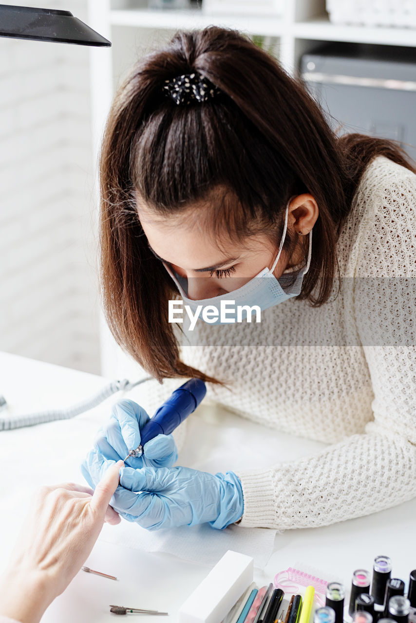 Young woman wearing glove and mask working at salon