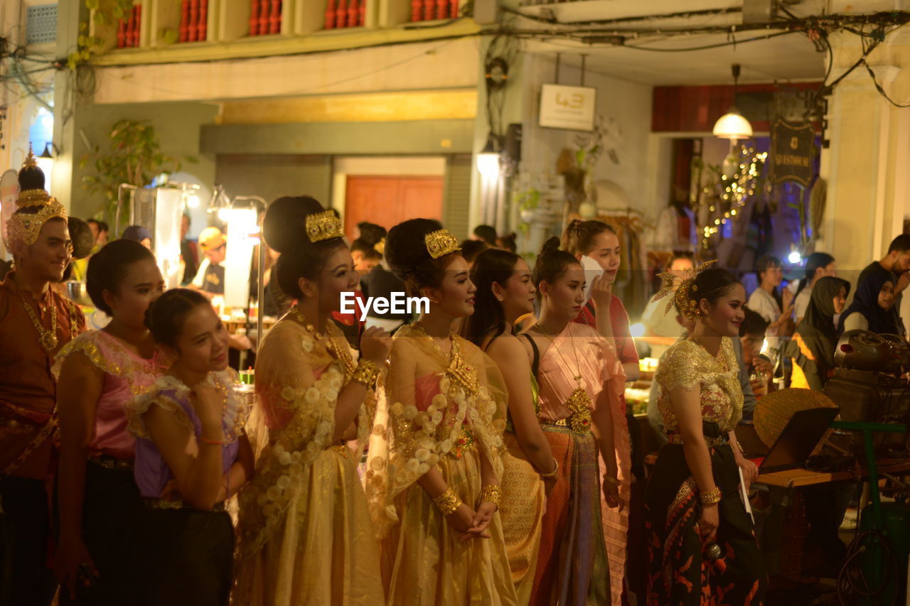 GROUP OF PEOPLE STANDING IN FRONT OF ILLUMINATED LANTERNS