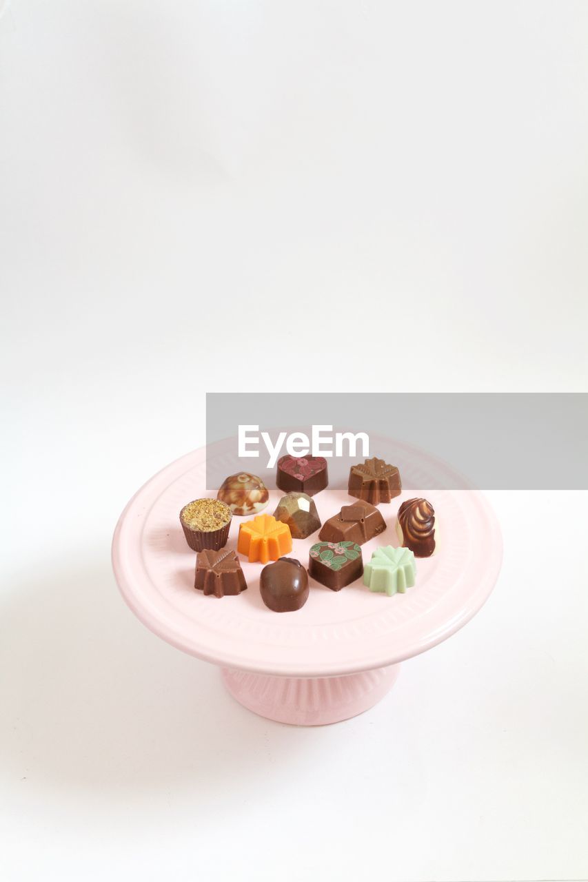 Close-up of chocolates on cakestand against white background