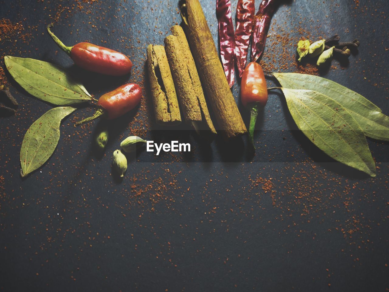 Bay leaves, cinnamon and chili at black background