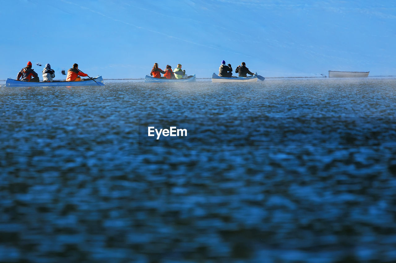 People in kayaks against sky