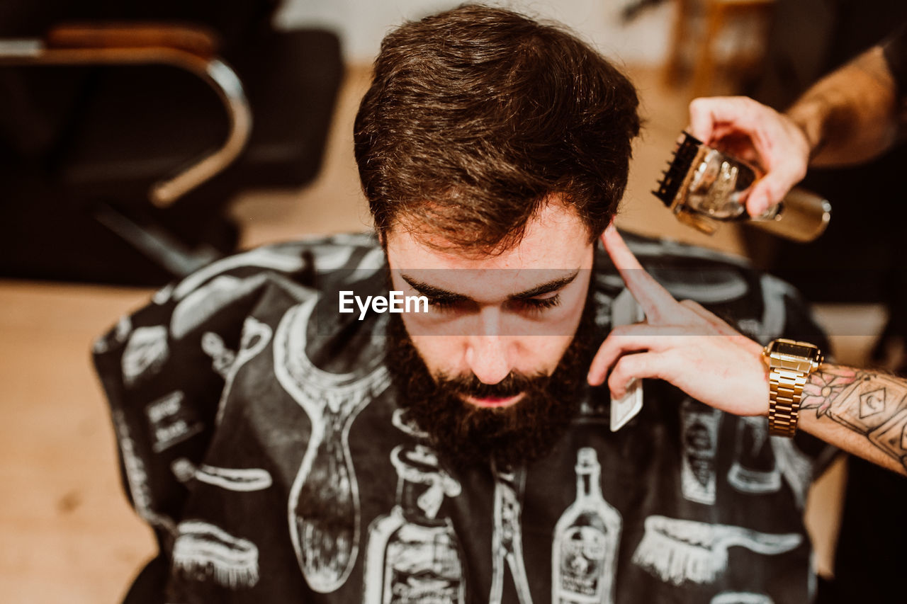 Cropped hands of barber grooming customer in salon