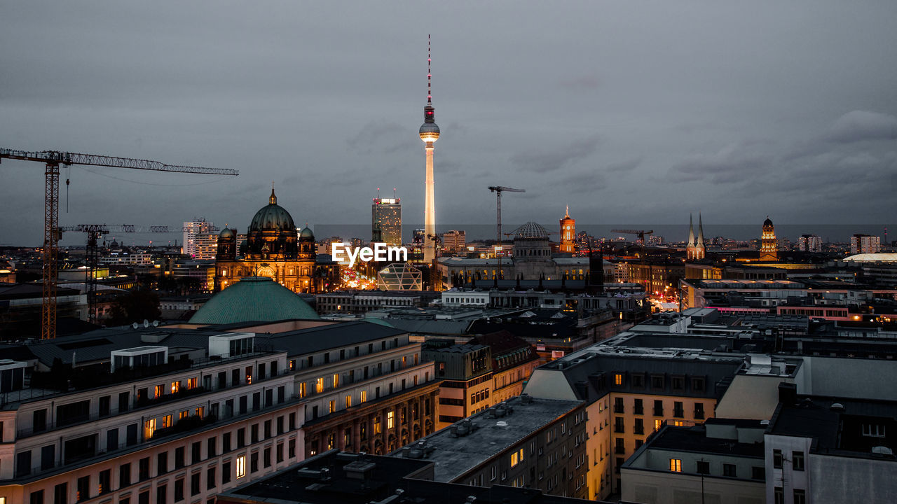 Illuminated fernsehturm and cityscape against sky