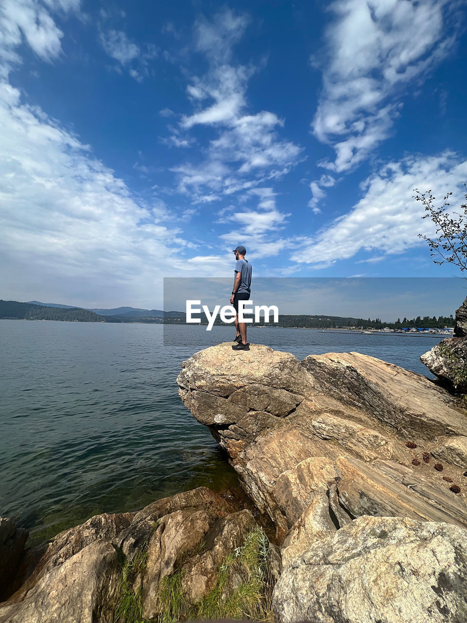 Rear view of man standing on rock by sea against sky