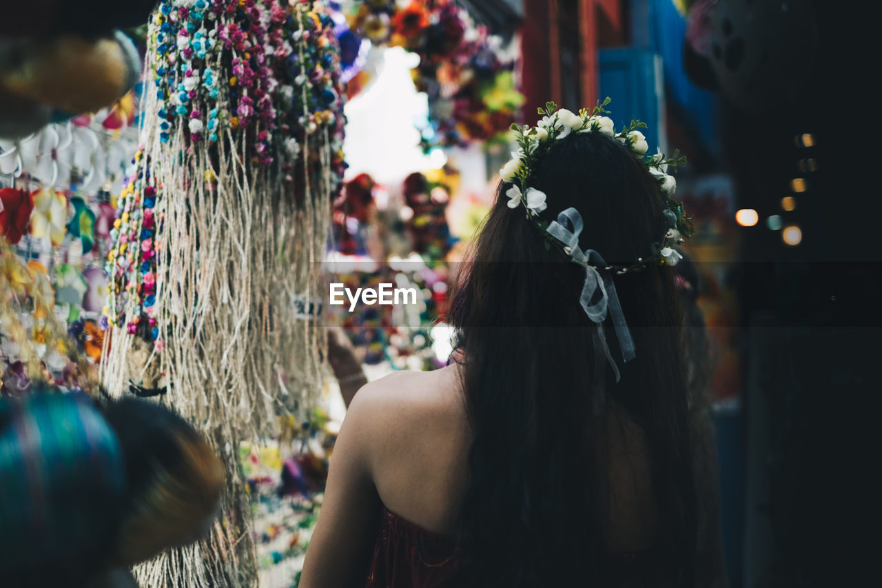 REAR VIEW OF WOMAN STANDING AT MARKET STALL