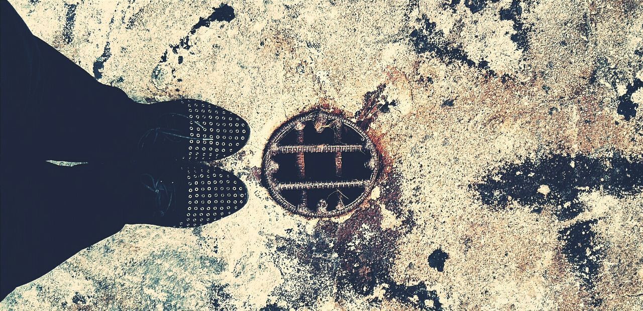 Low section of woman standing by sewer