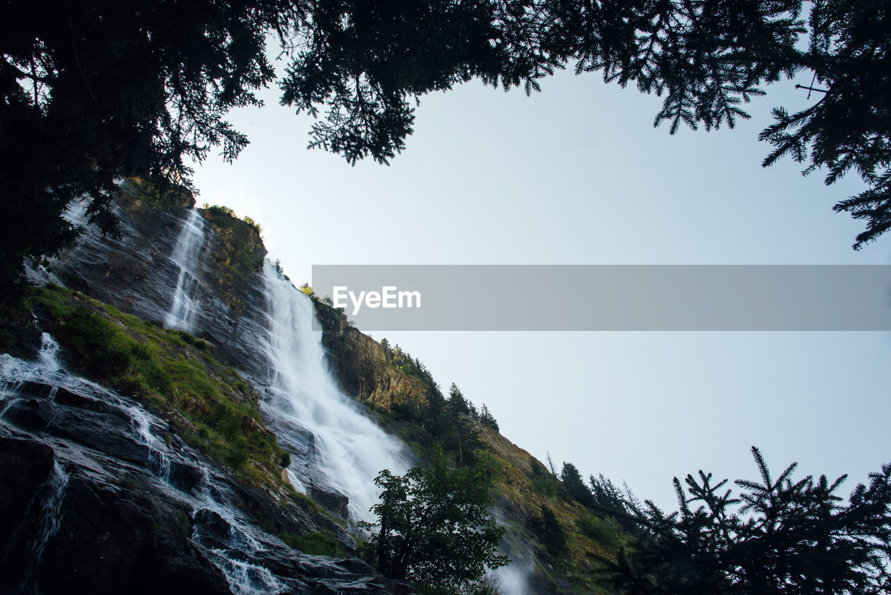 LOW ANGLE VIEW OF WATERFALL IN FOREST