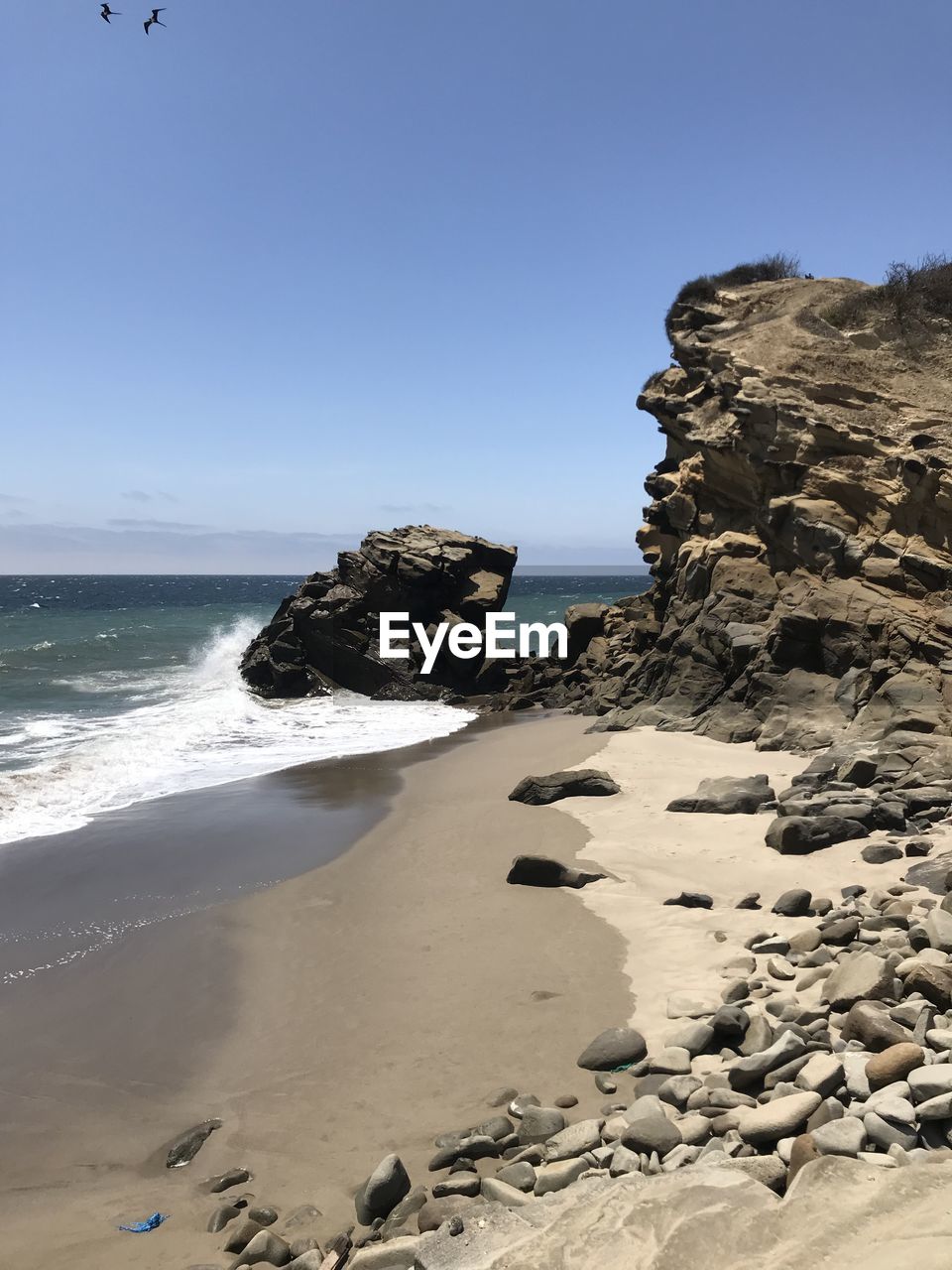 Rock formation on beach against clear sky