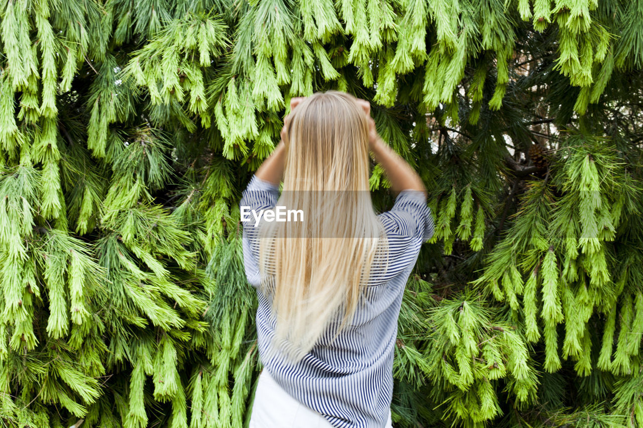 REAR VIEW OF WOMAN STANDING AT PLANTS