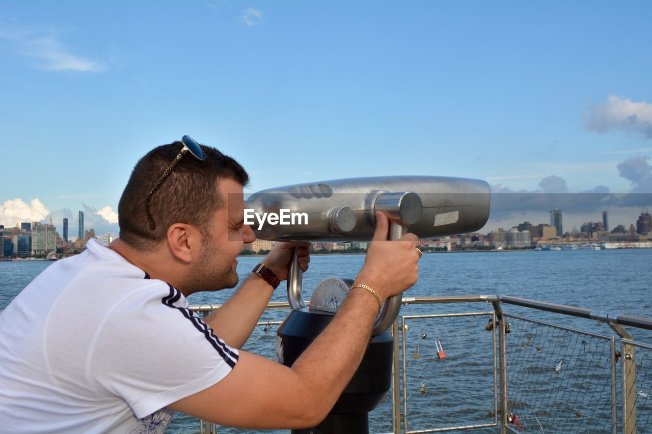 Man looking at sea through coin-operated binoculars