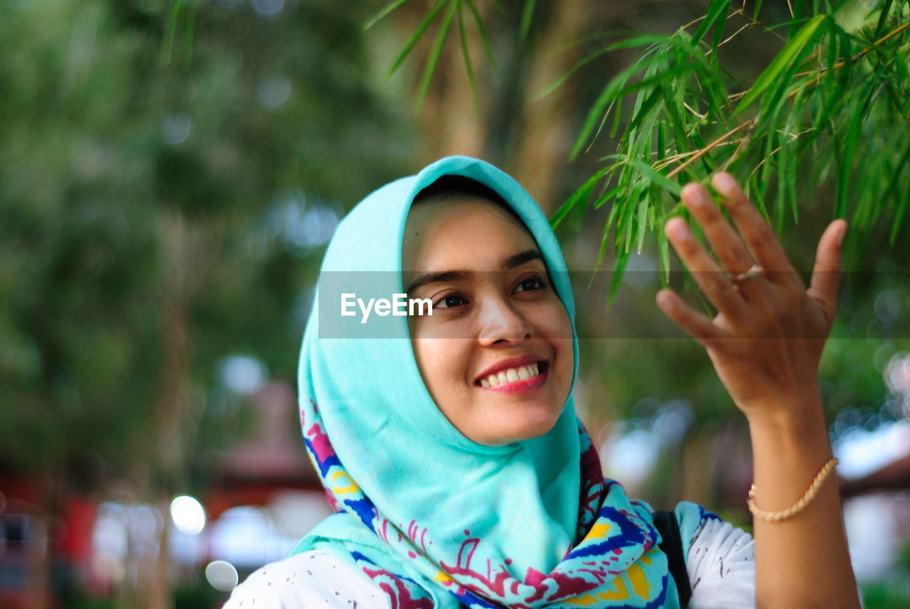 Close-up of woman wearing hijab looking at plant in park