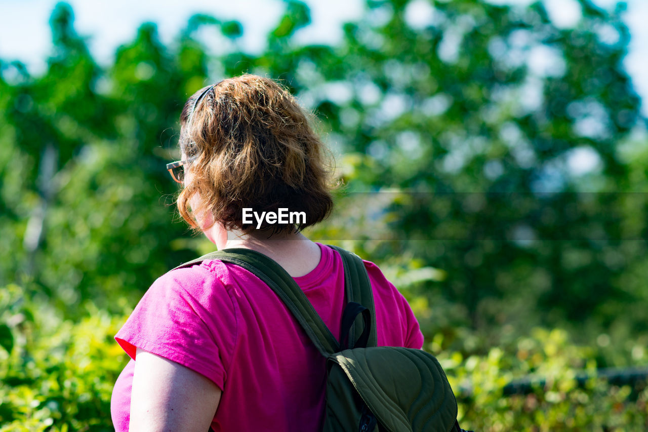 Woman with backpack by plants during sunny day