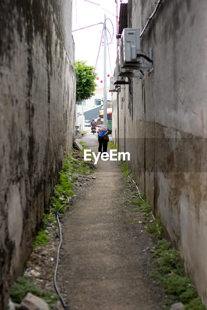 Man walking on alley amidst old buildings