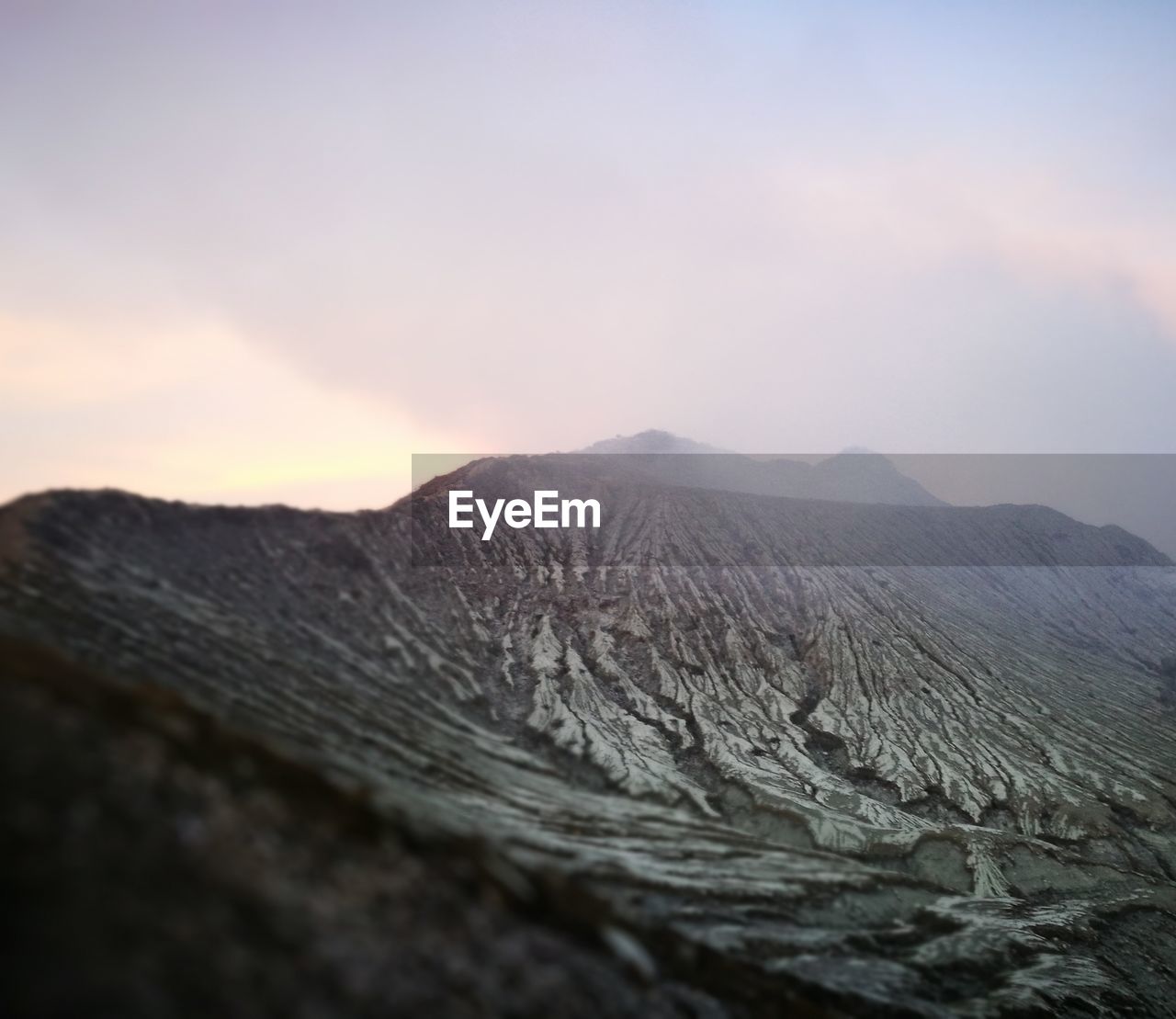 Scenic view of volcanic landscape against cloudy sky during sunset