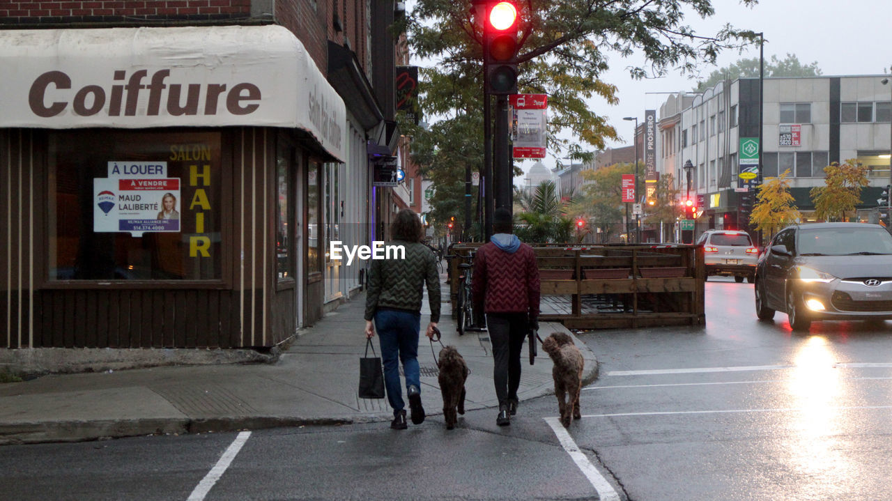 PEOPLE WALKING WITH DOG ON STREET IN CITY