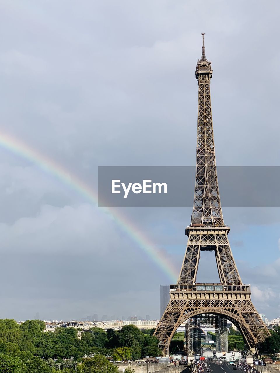 Low angle view of eiffel tower with rainbow against cloudy sky