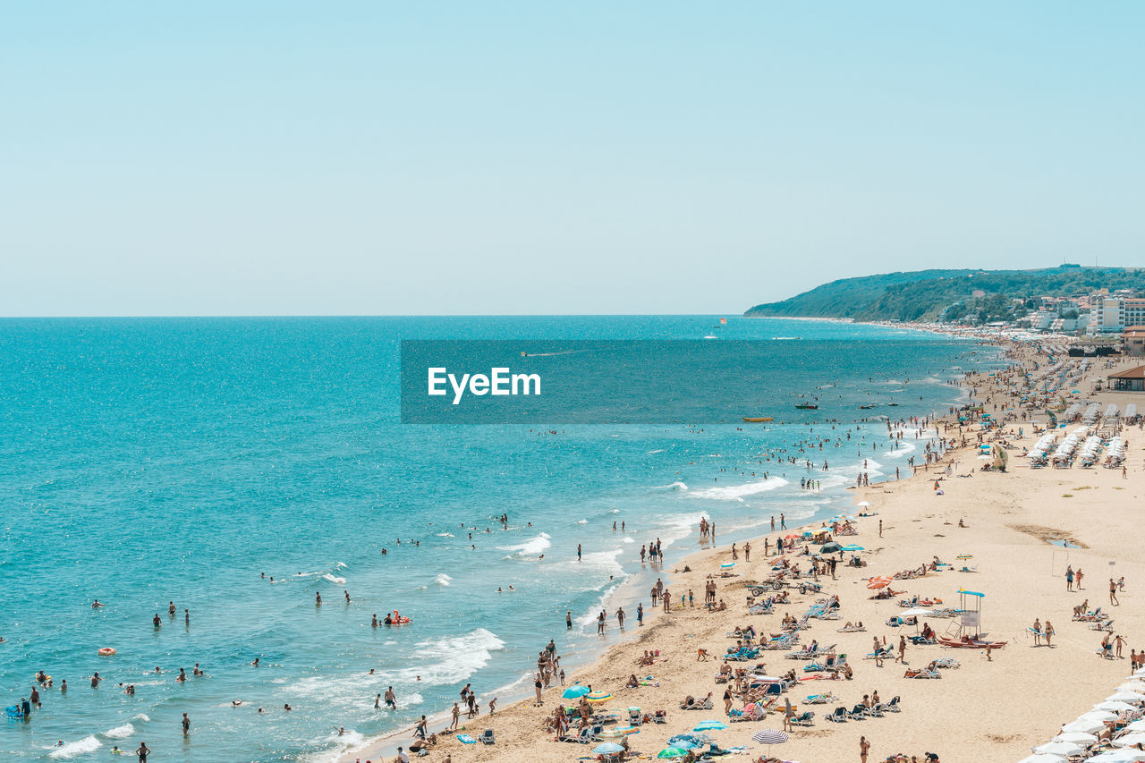 People on beach against clear sky