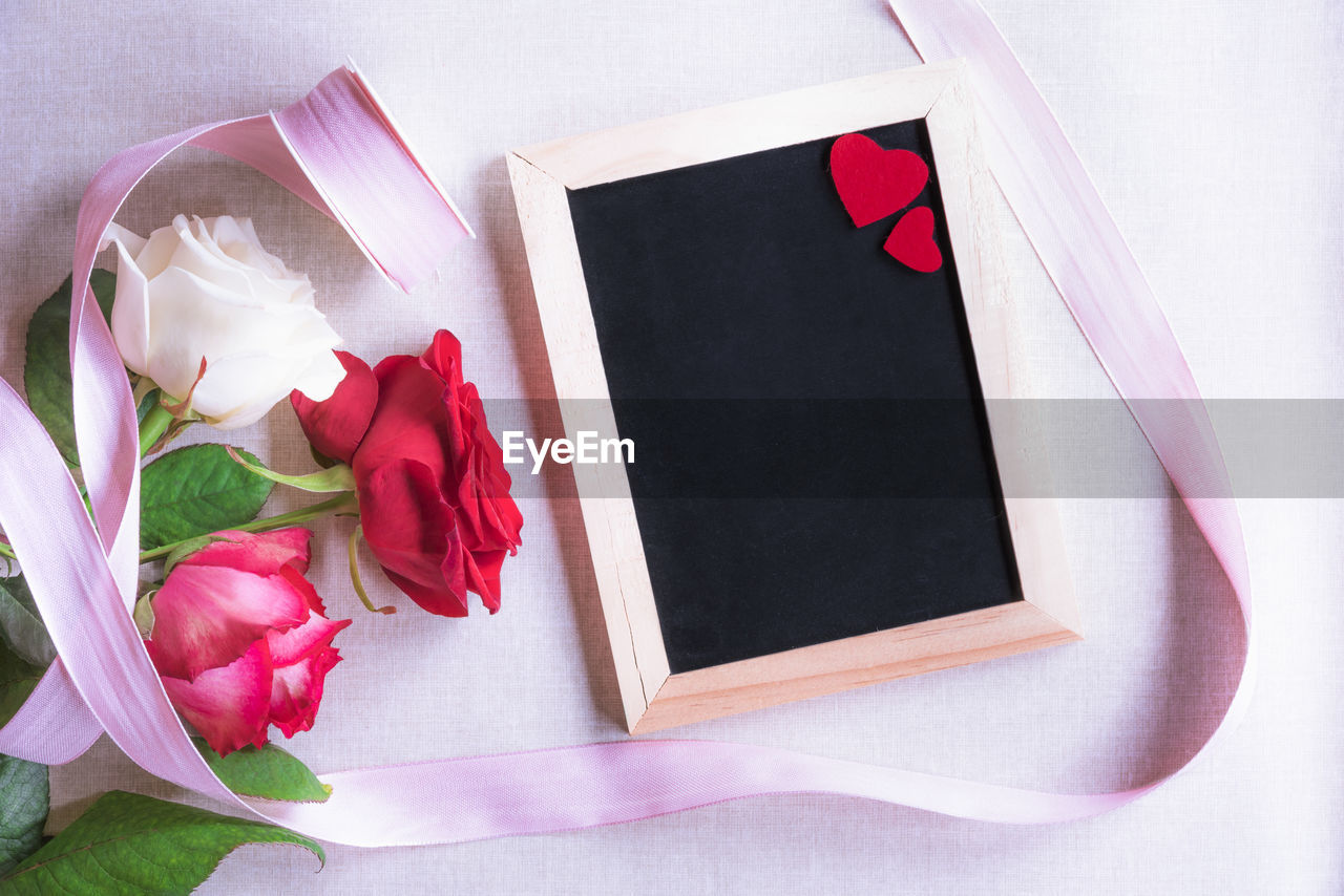 Close-up of flowers with ribbon and slate on table