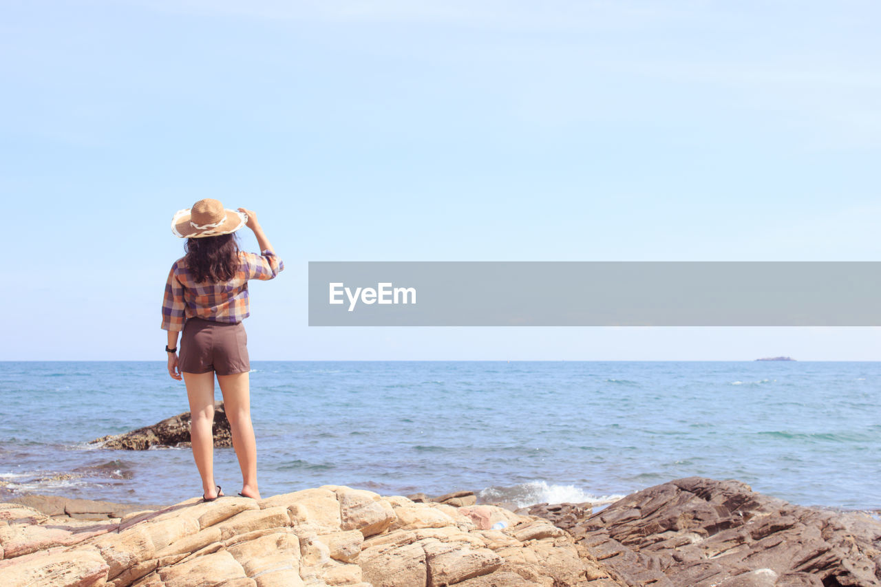 Rear view of man walking on beach against clear sky