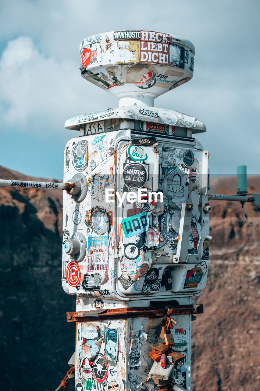 Close up of the old part of the abandoned car with some stickers against sky