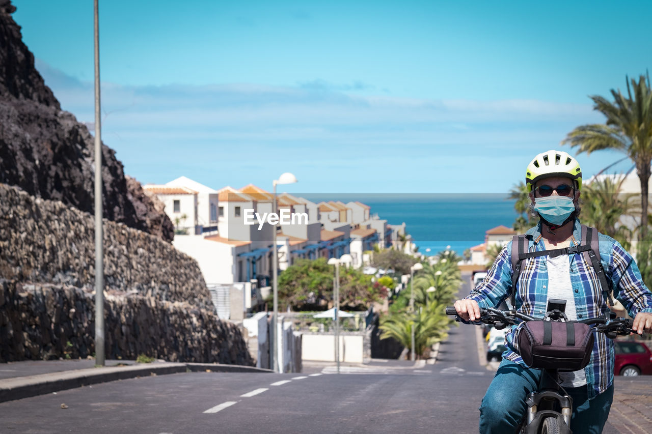 Portrait of woman riding motorcycle on road against sky