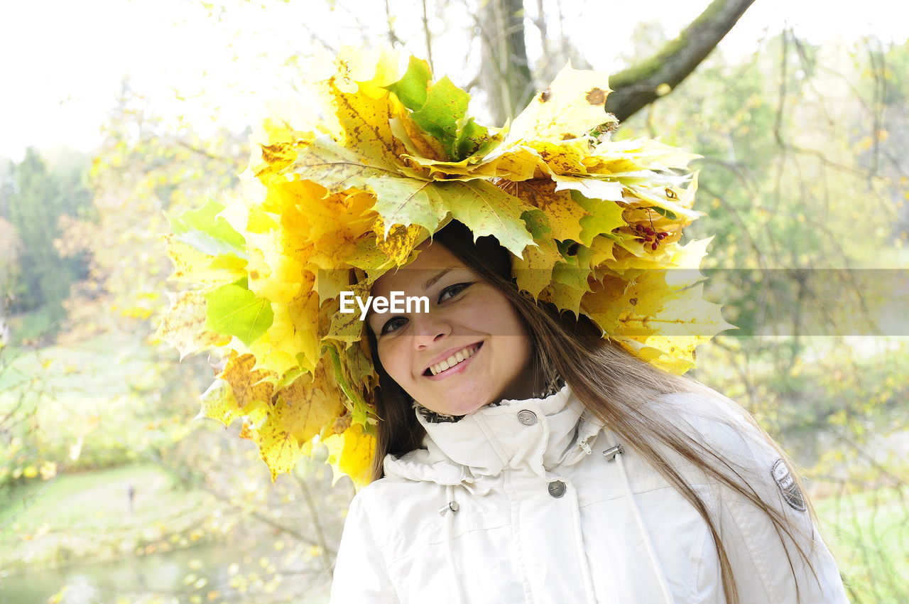 PORTRAIT OF A SMILING YOUNG WOMAN WITH YELLOW FLOWERS