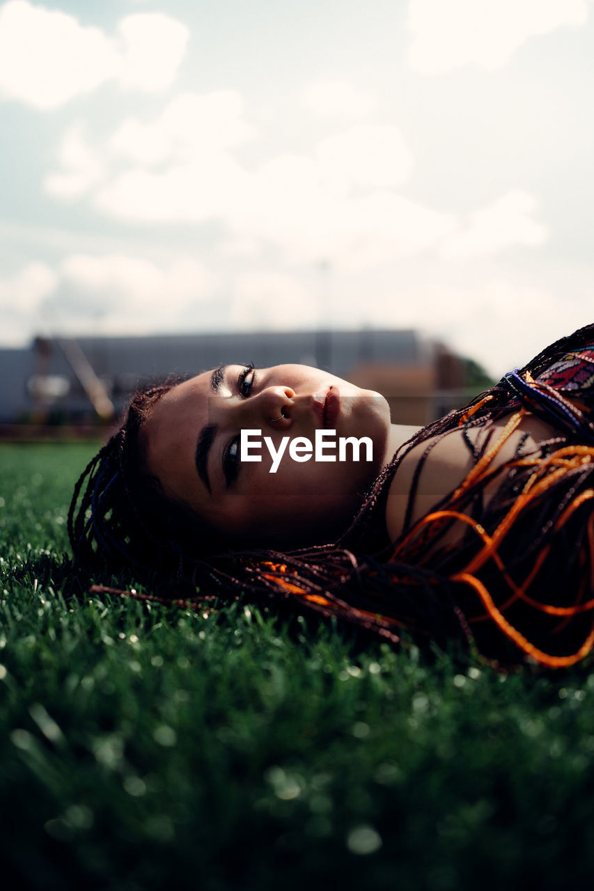 PORTRAIT OF YOUNG WOMAN LYING ON FIELD