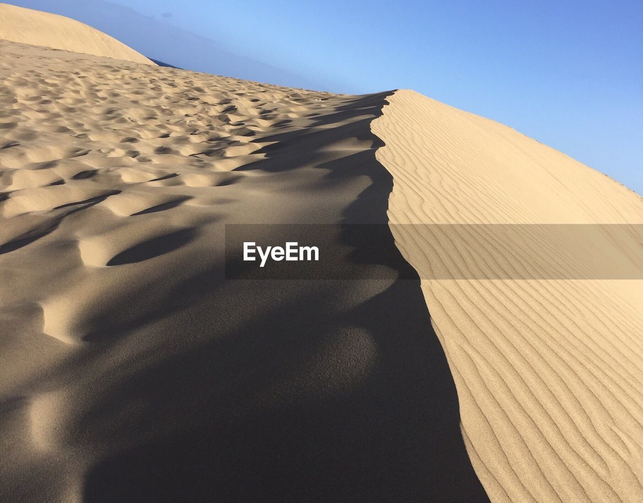 Sand dunes against clear sky