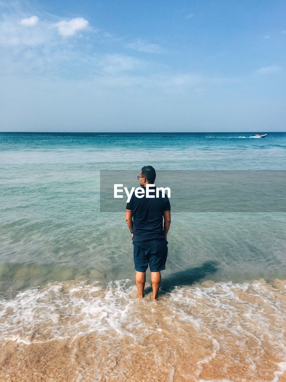 Rear view of man standing on beach against sky