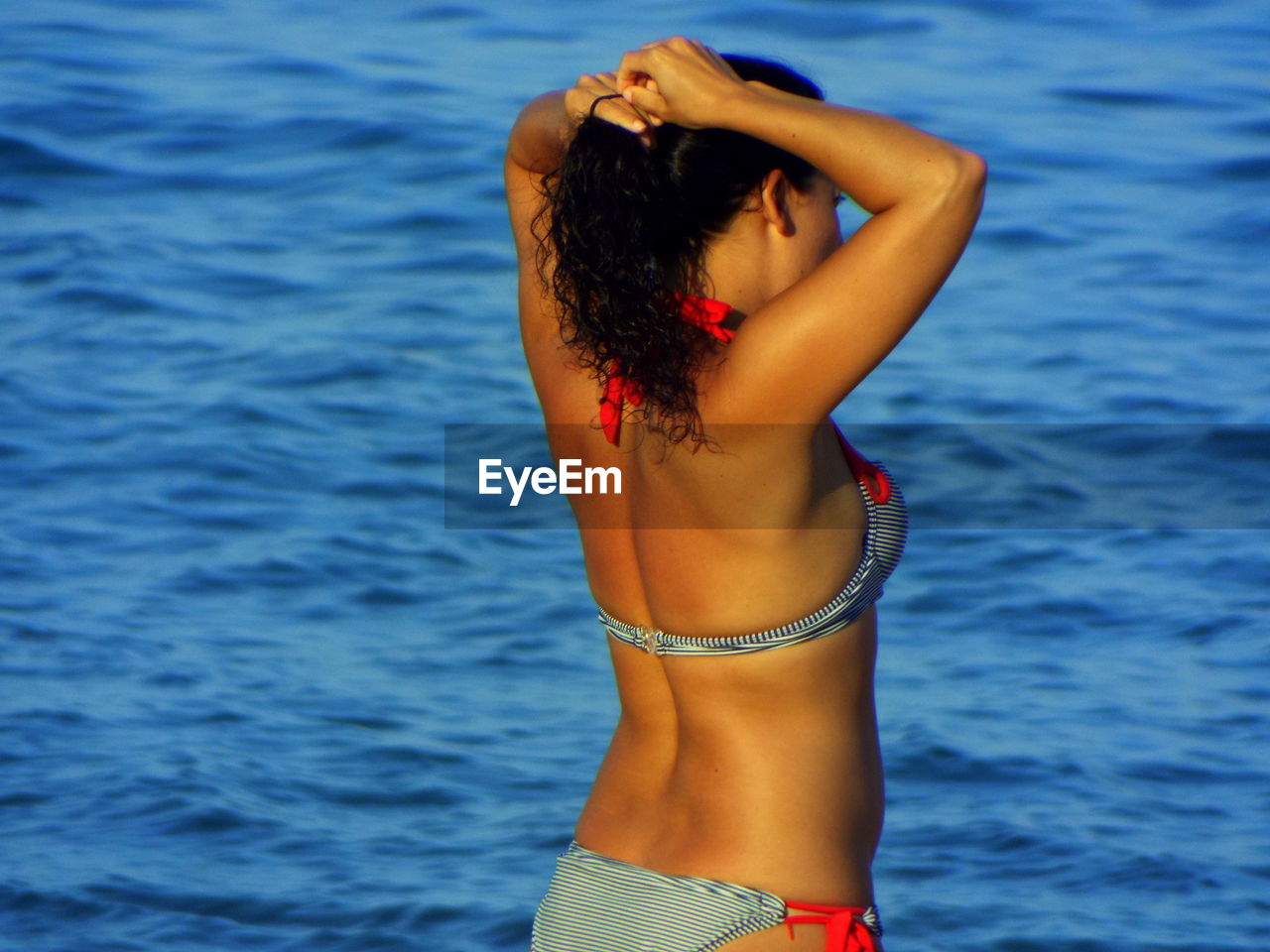 Woman in bikini standing against sea