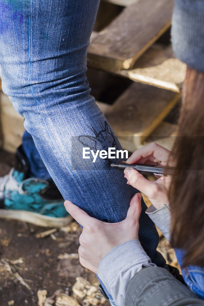 Cropped hand of woman drawing on friend leg