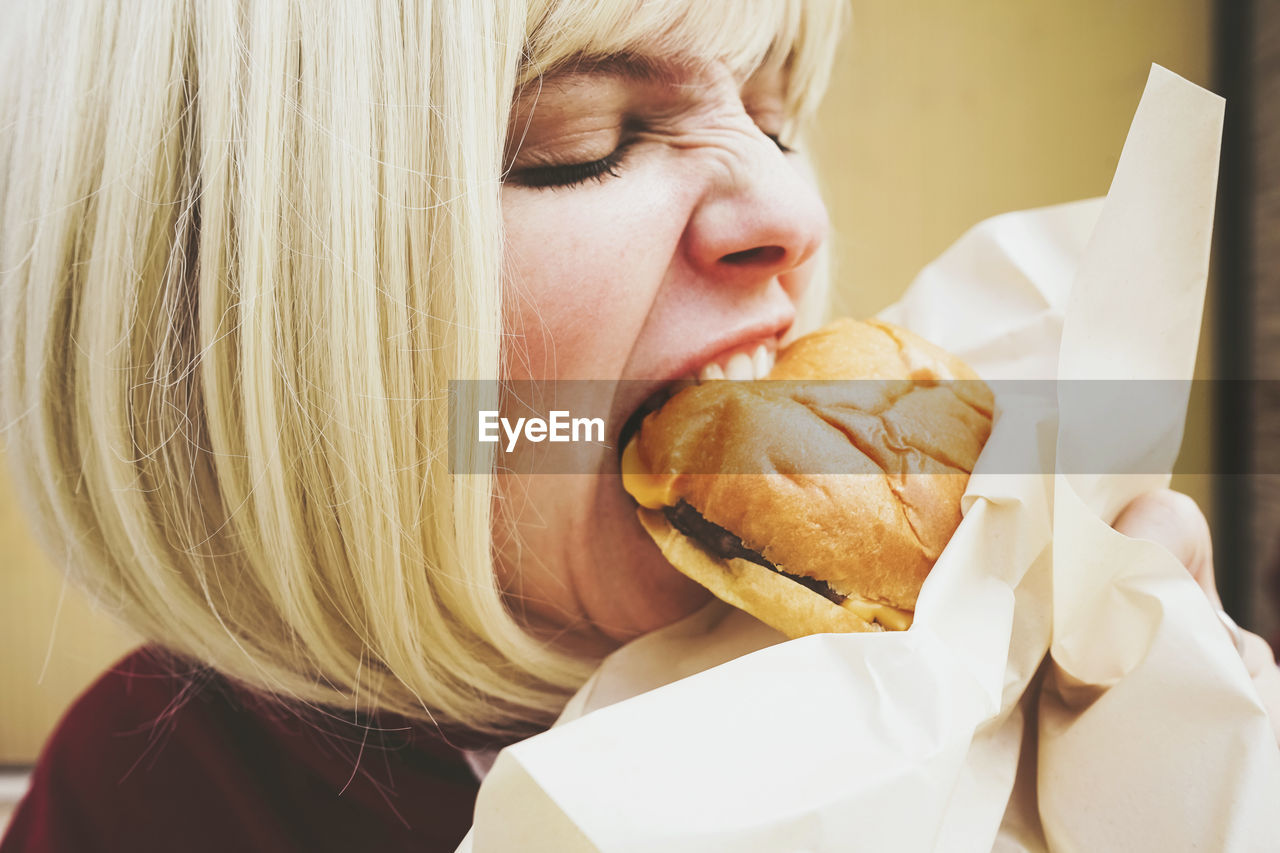 Woman with blond hair eating hamburger