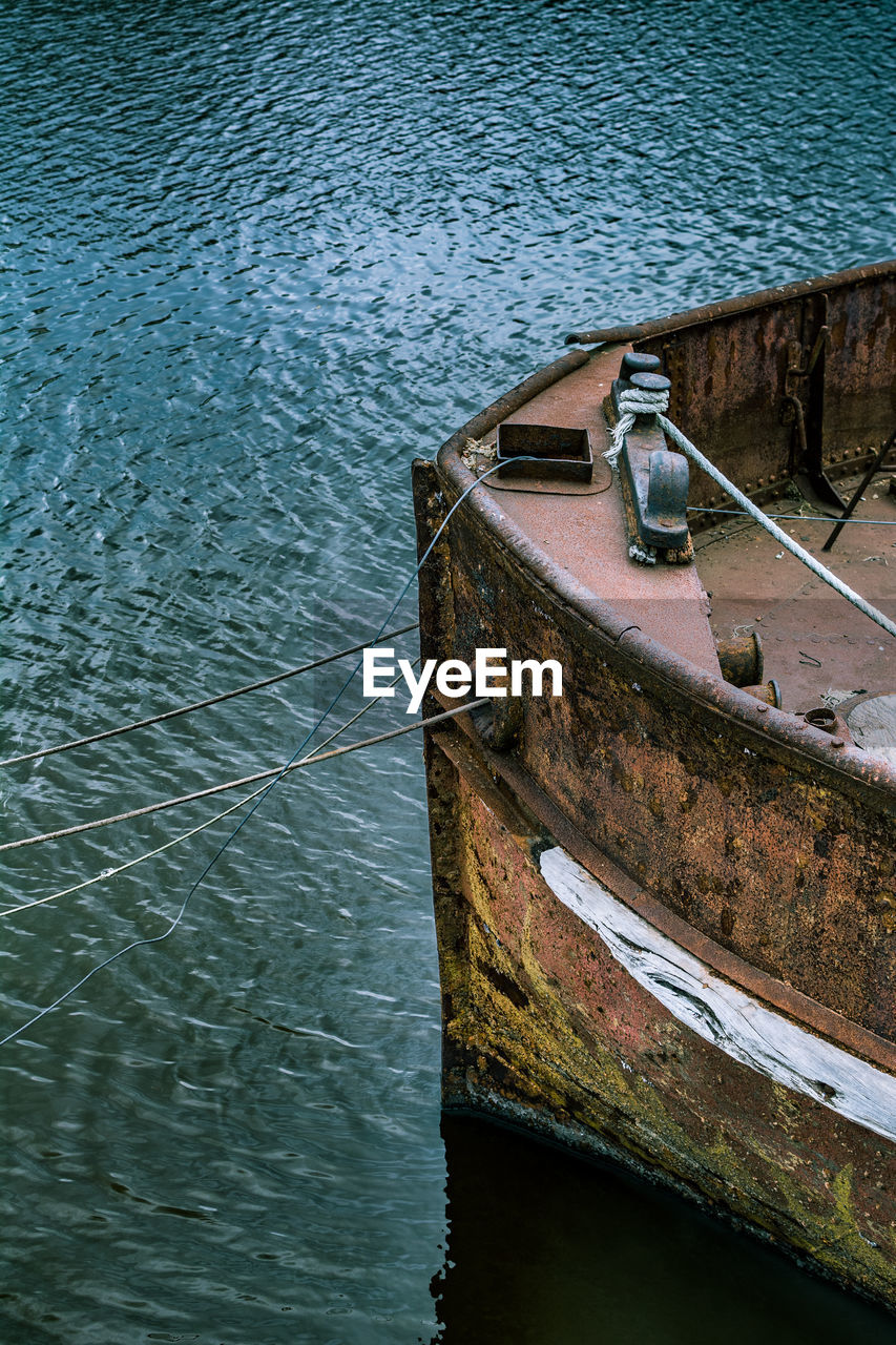 HIGH ANGLE VIEW OF OLD BOAT MOORED BY LAKE