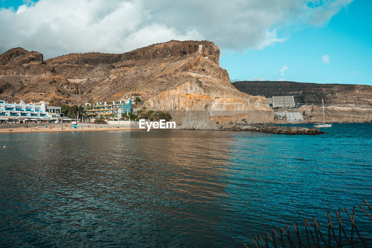 scenic view of sea by mountain against sky