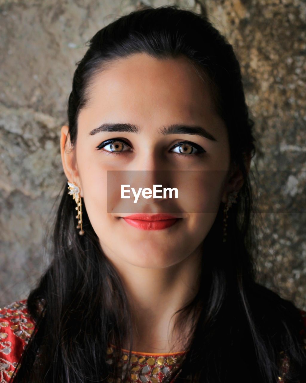 Close-up portrait of smiling beautiful woman against wall