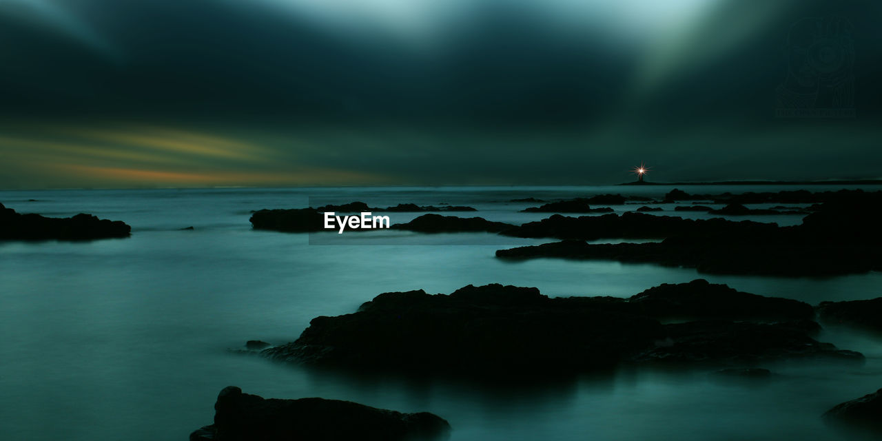 Scenic view of sea against dramatic sky at night