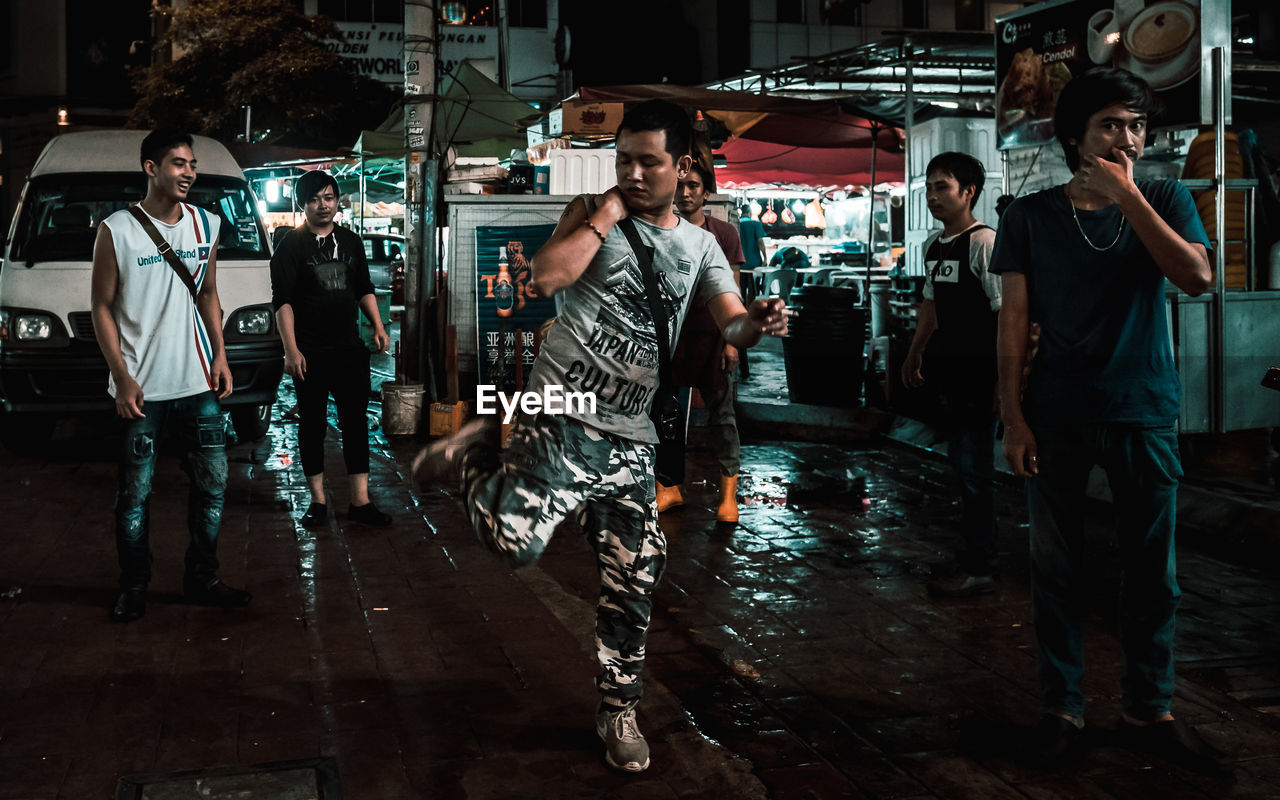 GROUP OF PEOPLE WALKING ON STREET IN CITY AT NIGHT