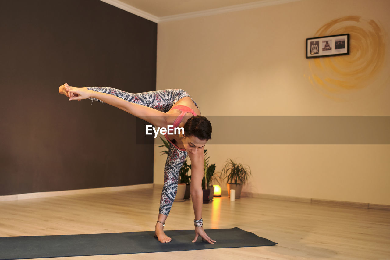 Young woman doing yoga on yoga mat in atmospheric yoga studio