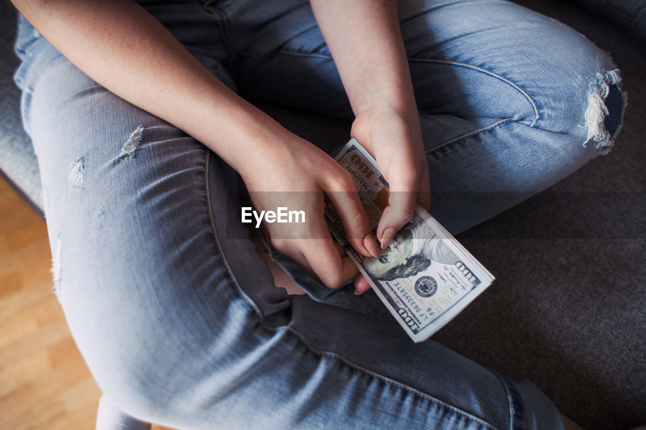 Midsection of woman holding us paper currency