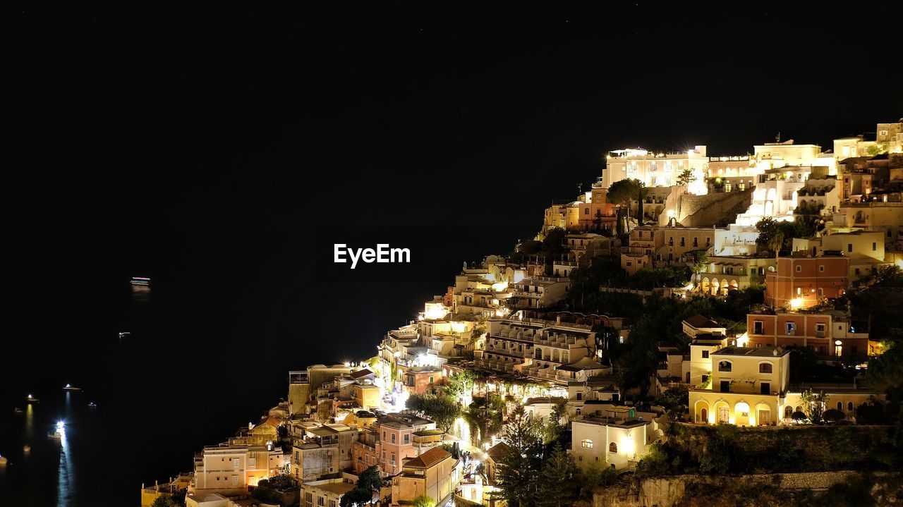 ILLUMINATED BUILDINGS IN CITY AGAINST CLEAR SKY