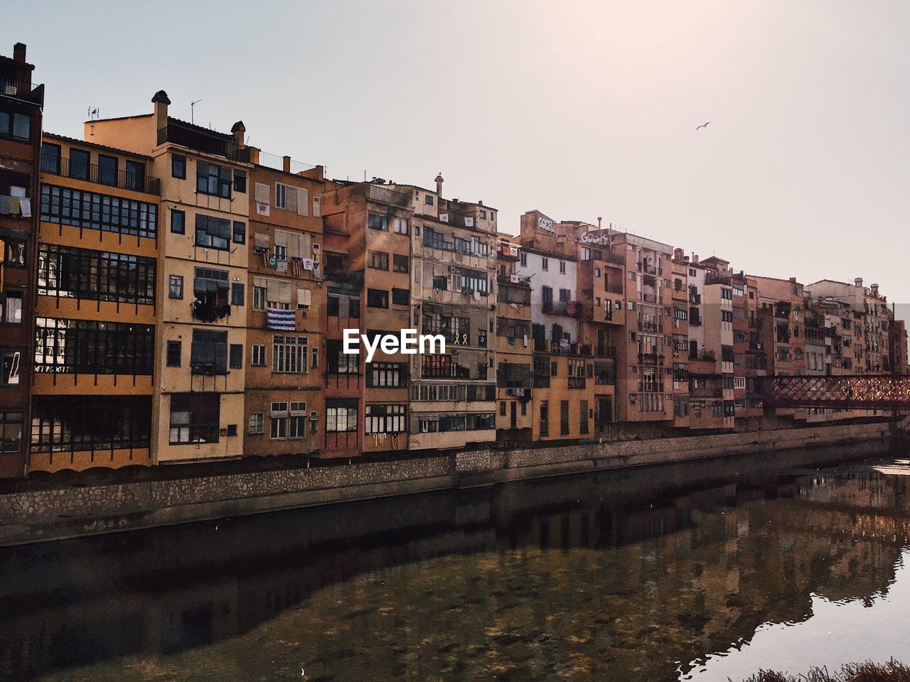 Buildings by river against sky in city